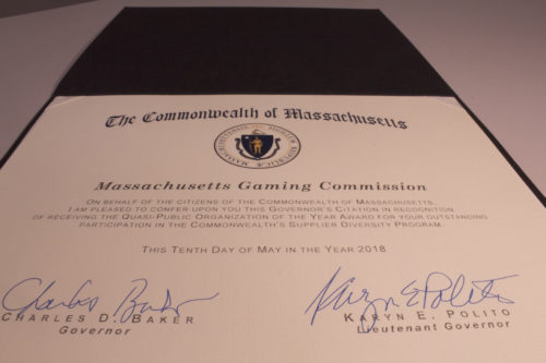 The citation signed by Governor Charlie Baker and Lieutenant Governor Karyn Polito. The text reads: "On behalf of the citizens of the Commonwealth of Massachusetts, I am pleased to confer upon you this Governor's Citation in recognition of receiving the Quasi-Public Organization of the Year Award for your outstanding participation in the Commonwealth's Supplier Diversity Program. This Tenth Day of May in the Year 2018. (Signed) Charles D. Baker, Governor. (Signed) Karyn E. Polito, Lieutenant Governor
